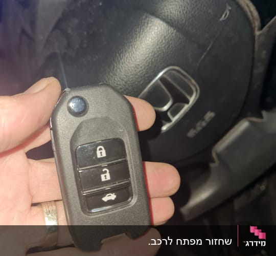 מפתח רכב עם שלושה כפתורים ביד אדם